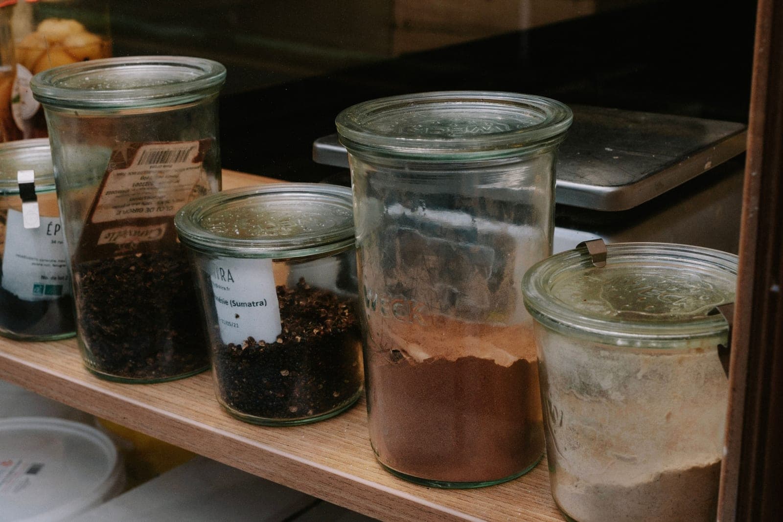 Glass jars of spices lined up on a kitchen shelf