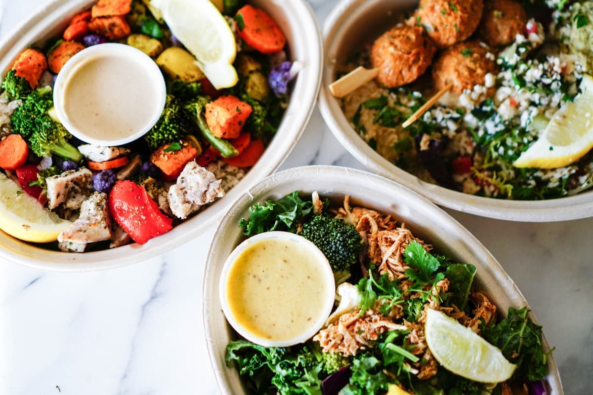 Illustrative stock photo: meal bowls with roasted vegetables, salad and sauces, seen from above