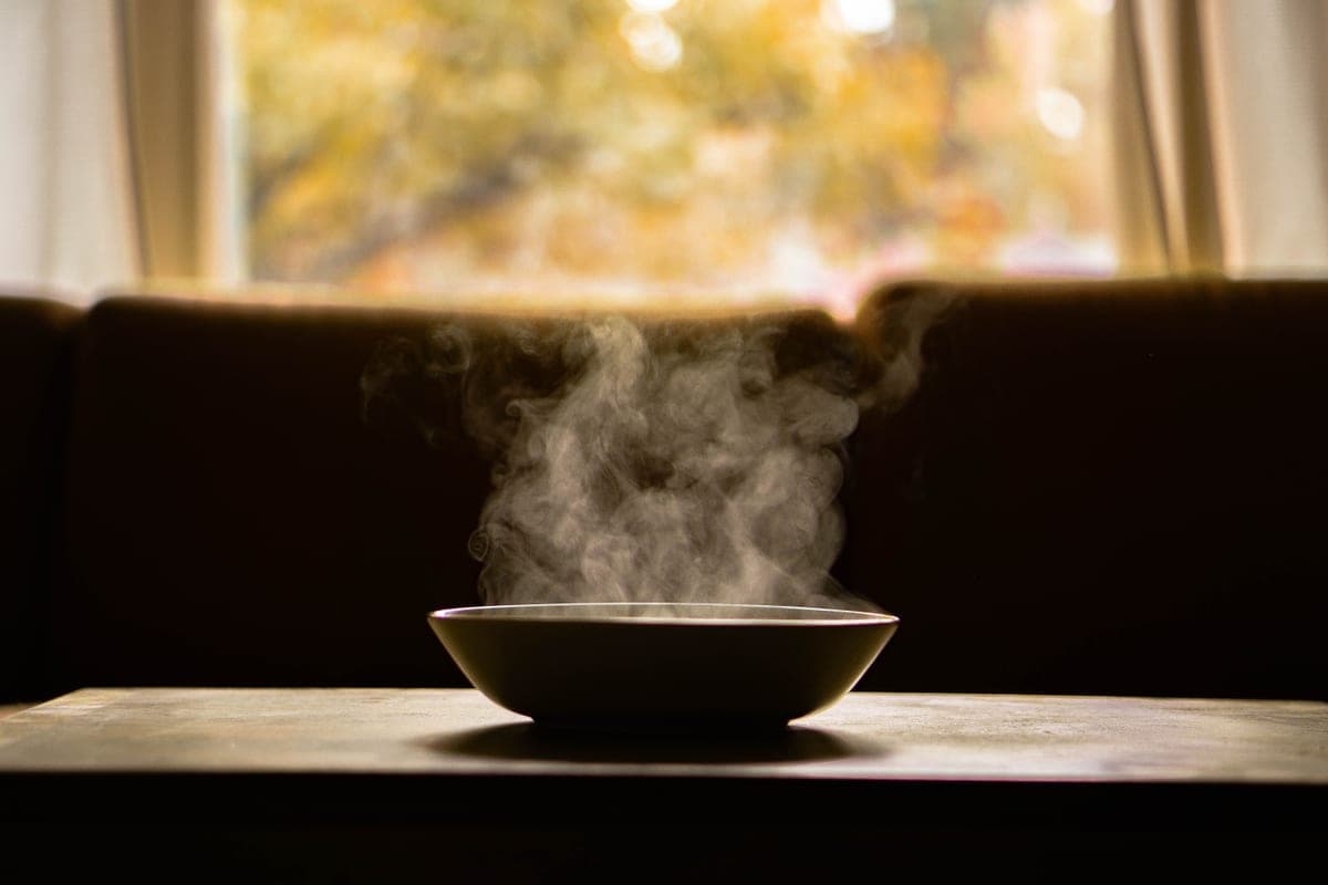 Illustrative stock photo: a steaming bowl of soup on a wooden table