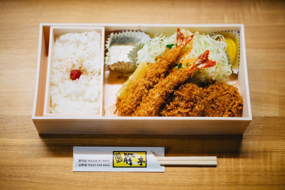 Illustrative stock photo: a bento box with rice, prawns and salad on a wooden table