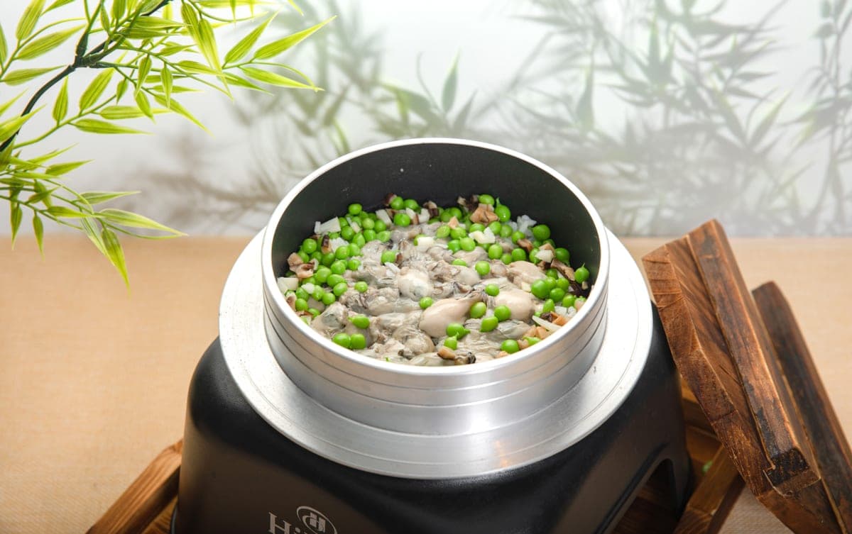 Illustrative stock photo: steamed rice with oysters and green peas in a rice cooker