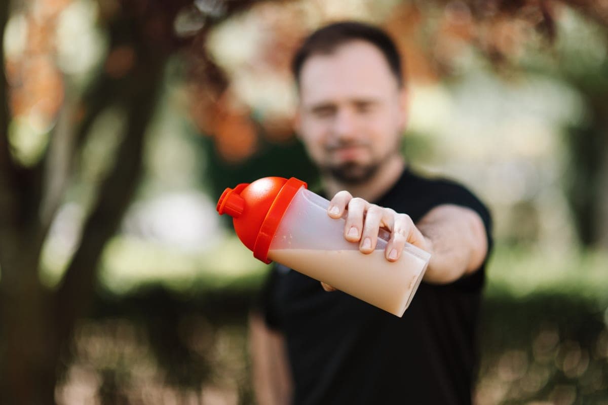 Illustrative stock photo: a man holding a plastic shaker bottle outdoors