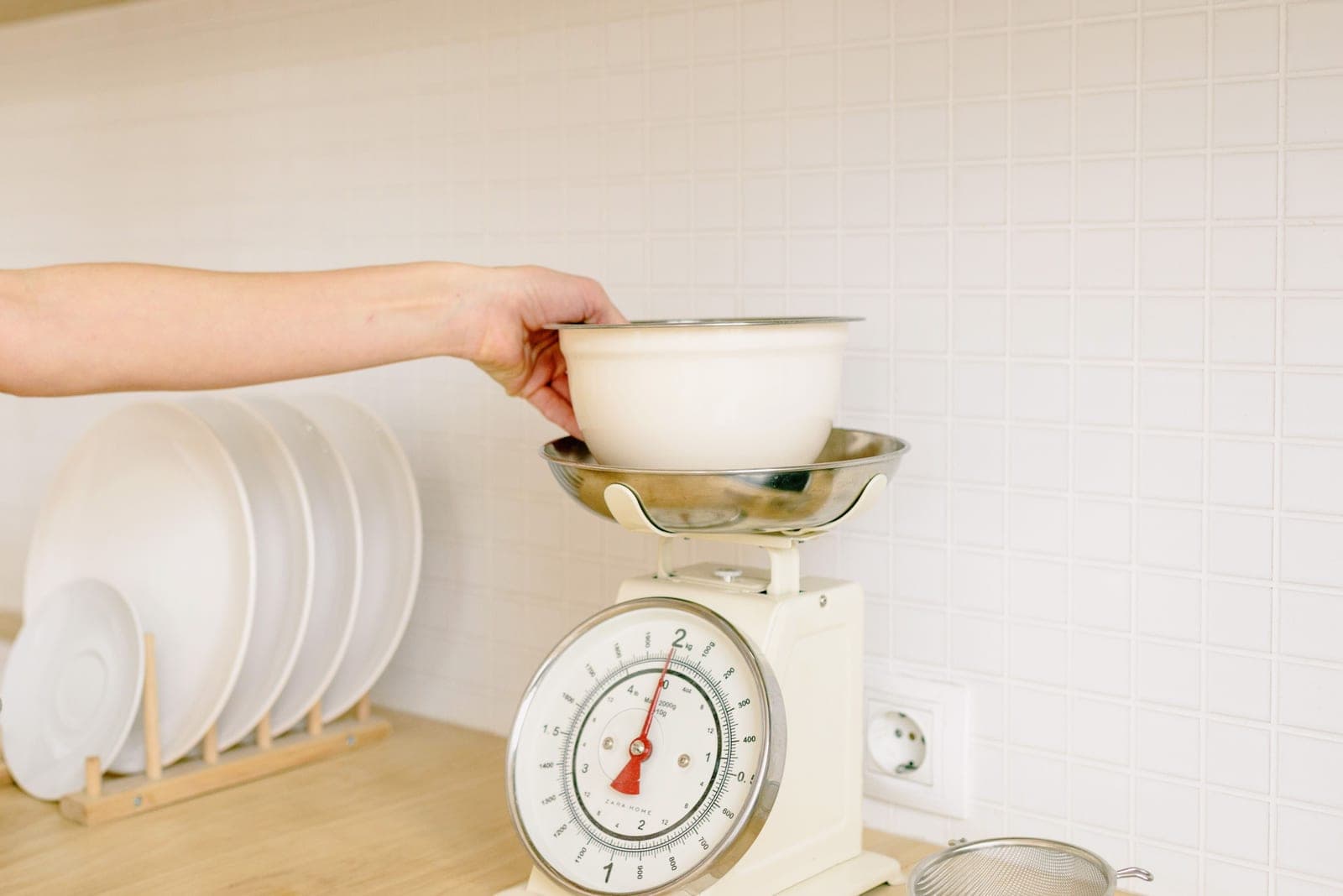 A hand placing a bowl on a digital kitchen scale